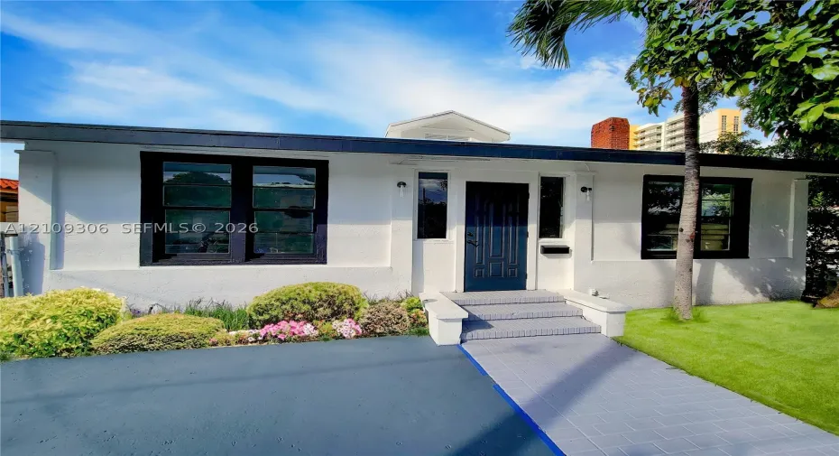 Stucco exterior featuring contrasting dark window trim, a recessed entry door, tiled front steps, and an asphalt driveway