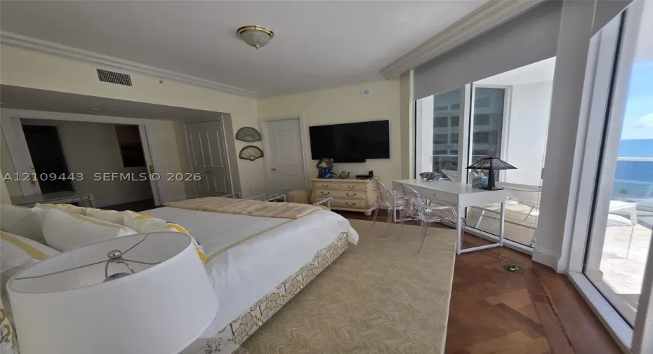 Herringbone-patterned wood-finish flooring, floor-to-ceiling glass sliding doors, crown molding, and recessed lighting