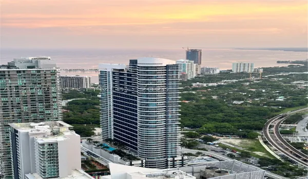 High-rise residential tower featuring a curved glass facade and a multi-level swimming pool terrace