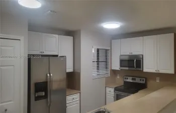 Kitchen featuring white shaker-style cabinetry, stainless steel appliances, neutral countertops, and flush-mount ceiling lighting