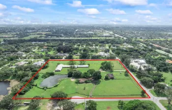Extensive acreage featuring expansive grassy grounds, a private pond, multiple structures, and perimeter fencing