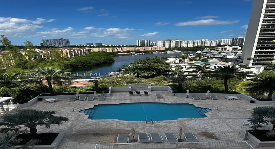 Outdoor swimming pool featuring a stone-paved deck, perimeter planter beds, and surrounding landscape greenery