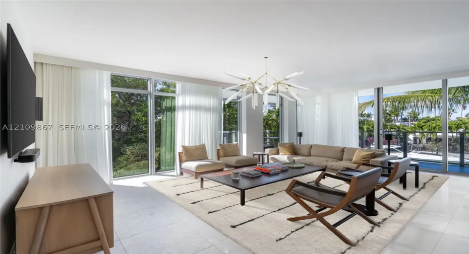 Floor-to-ceiling windows, large-format tile flooring, and a multi-arm geometric chandelier