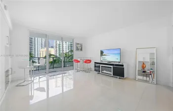 Living area featuring large-format tile flooring, floor-to-ceiling glass sliding doors, and built-in cabinetry