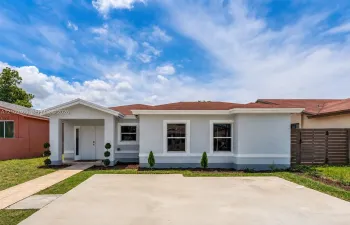 Single-story residence featuring a light-toned stucco exterior, asphalt shingle roof, double-entry front doors, concrete driveway, and a horizontal-slat privacy fence