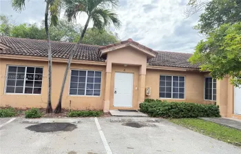 Stucco exterior with a tiled roof, multi-pane grid windows, and dedicated parking space