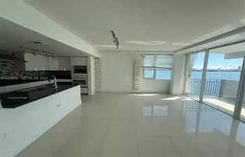 Kitchen featuring white cabinetry, dark countertops, a tiled backsplash, and built-in stainless steel oven, finished with large-format tile flooring and floor-to-ceiling glass sliding doors opening to an exterior balcony