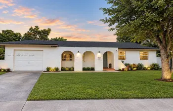 Single-story exterior featuring white stucco finish, arched entryways, a dedicated one-car garage, and a manicured front lawn