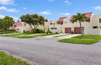 Stucco exterior featuring red tile roof accents, integrated garages, and manicured landscaping