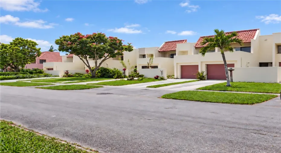 Stucco exterior featuring red tile roof accents, integrated garages, and manicured landscaping