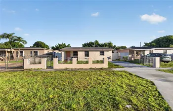 Single-story residence featuring a low-slope roof, stucco exterior, concrete driveway, and front perimeter wall with metal fencing
