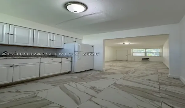 Kitchen featuring white cabinetry, speckled stone countertops, and large-format porcelain tile flooring with veined detailing