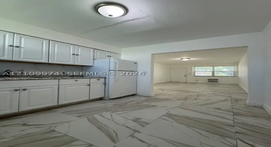 Kitchen featuring white cabinetry, speckled stone countertops, and large-format porcelain tile flooring with veined detailing