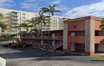 Two-story exterior with stucco finish, integrated outdoor staircase, metal railings, and dedicated asphalt parking