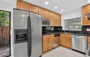 Kitchen featuring natural wood cabinetry, stone countertops, stainless steel appliances, recessed lighting, and tile flooring