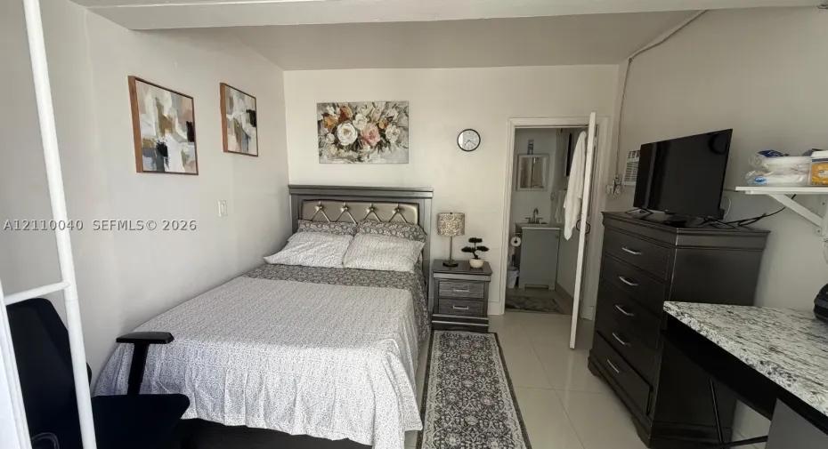 Neutral-toned interior featuring tiled flooring and a wall-mounted shelving unit with a stone-finish countertop