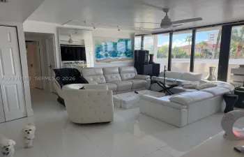 Living area featuring large-format tile flooring, floor-to-ceiling windows, full-length wall mirror, ceiling fan, and adjustable track lighting