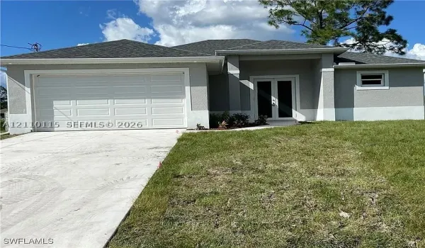Single-story exterior featuring a stucco facade, double-door entry, concrete driveway, and a two-car garage
