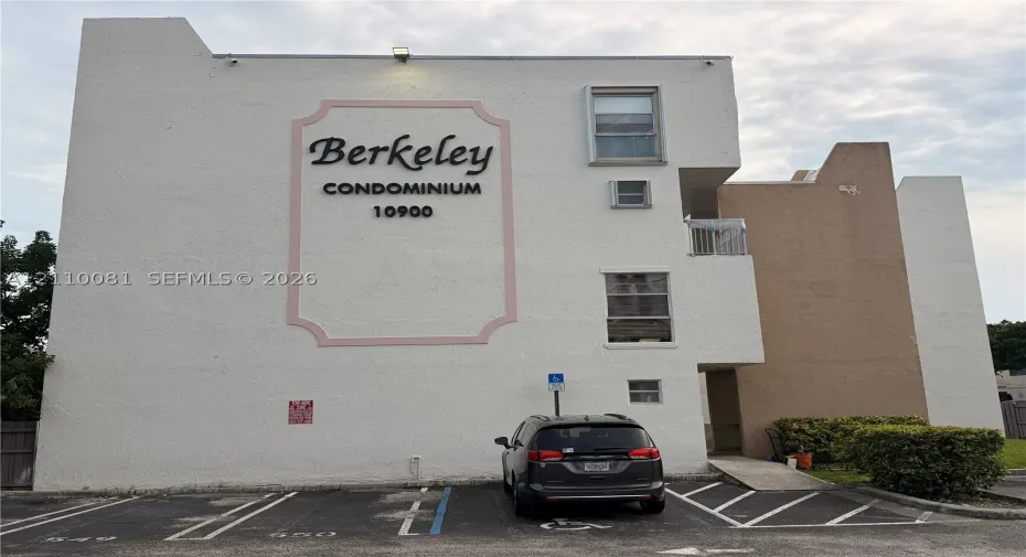 Exterior facade featuring a stucco finish, multi-level building design, dedicated parking stalls, and paved access ramp