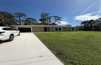 Single-story residence featuring a concrete driveway, attached garage, and expansive lawn