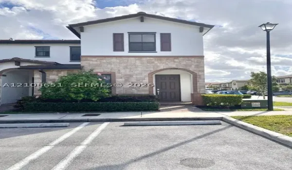 Exterior featuring stone veneer facade, neutral stucco finish, decorative shutters, and an arched entry