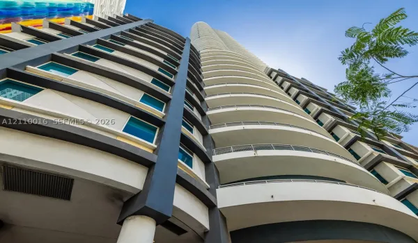 High-rise architecture featuring a curvilinear facade, tiered balconies with metallic railings, and dark-toned structural columns