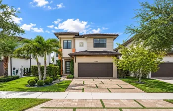 Two-story exterior featuring a contemporary facade, multi-tonal stucco finish, tile roof, multi-car garage, and a paver driveway with turf accents