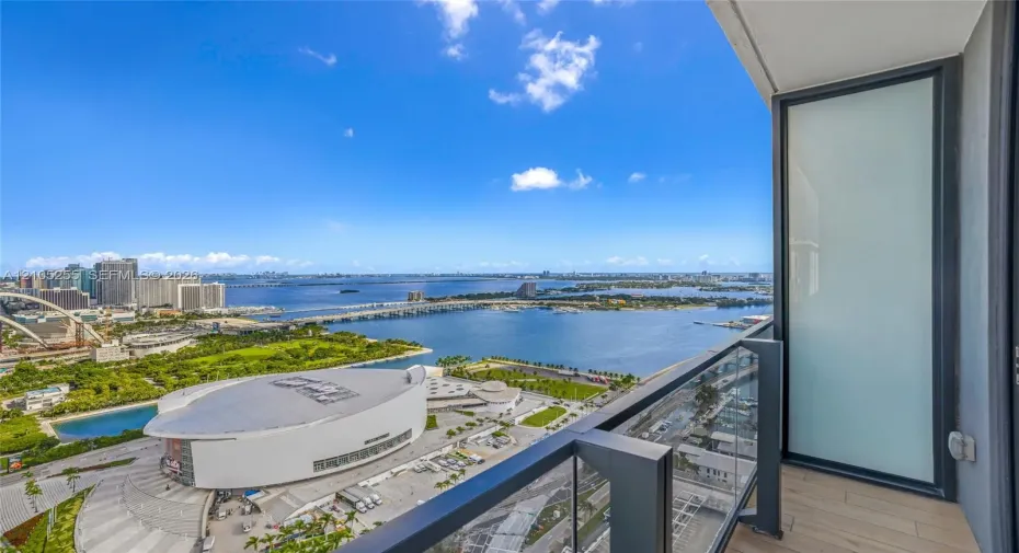 Private balcony featuring a glass-panel railing, frosted glass partition, and wood-finish flooring