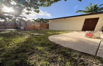 Exterior space featuring a concrete patio, horizontal wood slat privacy fencing, and mature palm trees