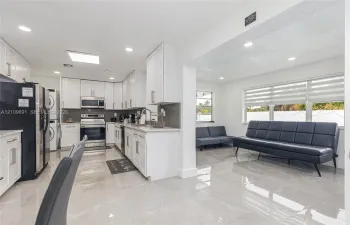 Kitchen featuring white shaker cabinetry, stone-finish countertops, stainless steel appliances, and large-format tile flooring