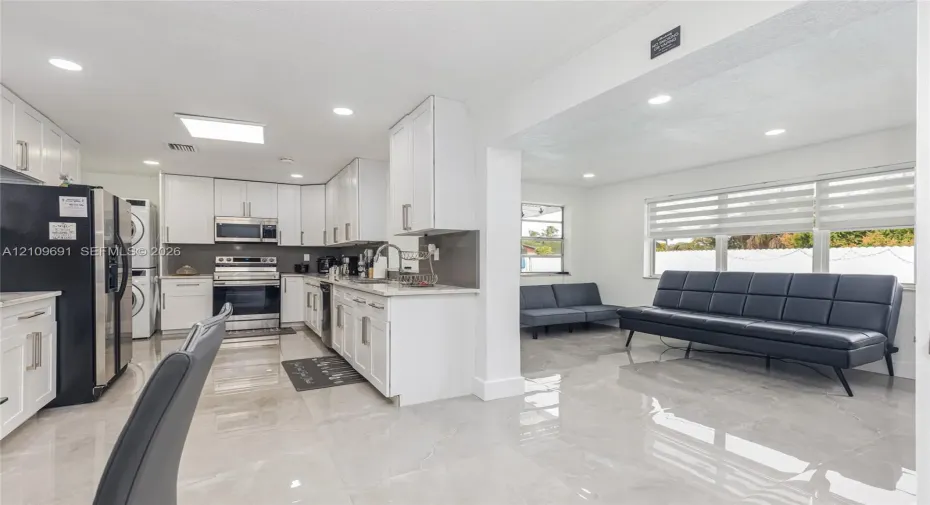 Kitchen featuring white shaker cabinetry, stone-finish countertops, stainless steel appliances, and large-format tile flooring