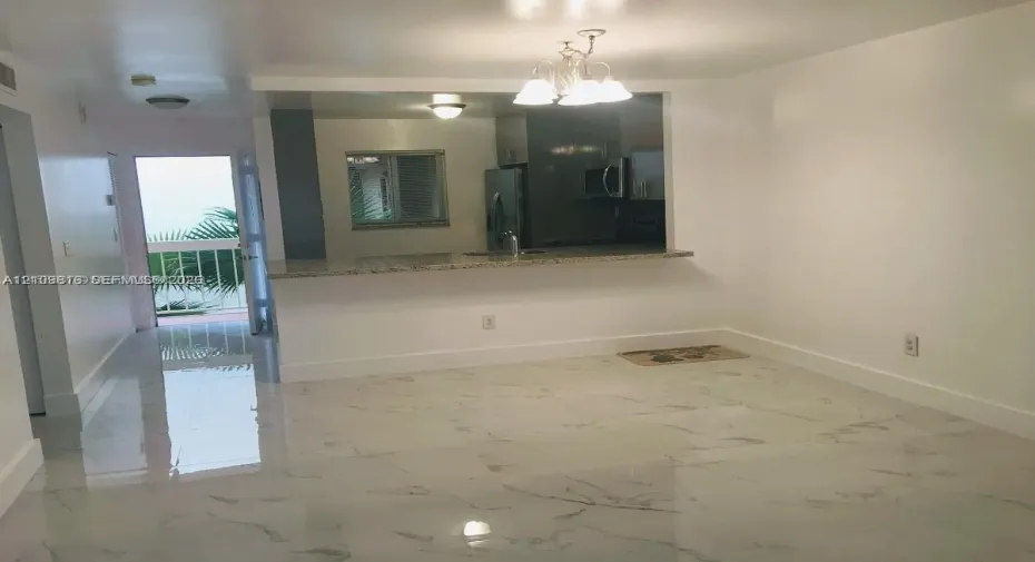 Large format polished tile flooring, kitchen featuring a stone-surface breakfast bar, and an overhead multi-light fixture