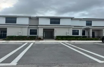 Two-story exterior featuring a neutral stucco and horizontal siding facade, dark-tinted windows, and a covered entryway