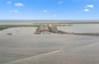 Aerial perspective of coastal landscape featuring expansive open water, a bridge, and a land-based thoroughfare
