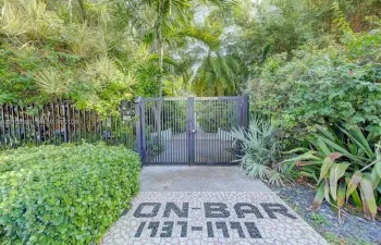 Gated entrance featuring decorative mosaic tile stone paving and mature tropical landscaping