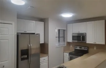 Kitchen featuring white shaker-style cabinetry, stainless steel appliances, neutral countertops, and flush-mount ceiling lighting