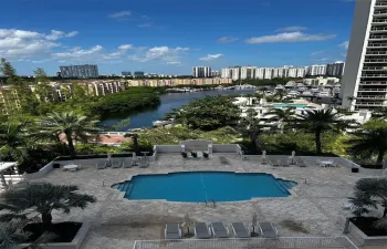 Outdoor swimming pool featuring a stone-paved deck, perimeter planter beds, and surrounding landscape greenery