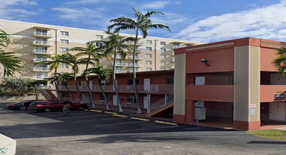 Two-story exterior with stucco finish, integrated outdoor staircase, metal railings, and dedicated asphalt parking