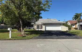 Single-story residence featuring a textured stone facade, a multi-paneled garage door, a tiled roof, and an asphalt driveway
