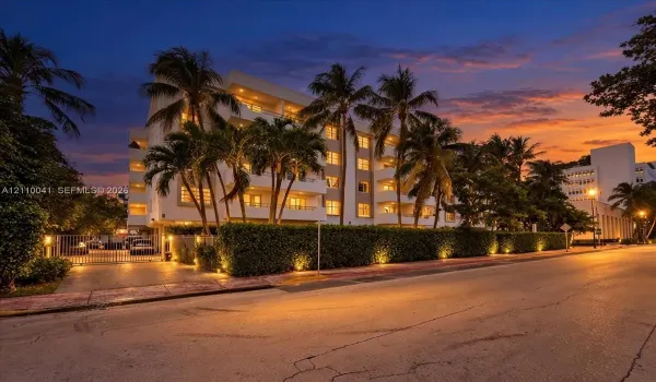 Multi-story residential building featuring private balconies, integrated landscape lighting, and a gated entrance