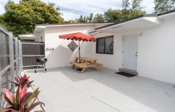 Concrete patio featuring a vertical wood-slat privacy fence, exterior white stucco siding, and dark-trimmed window frames