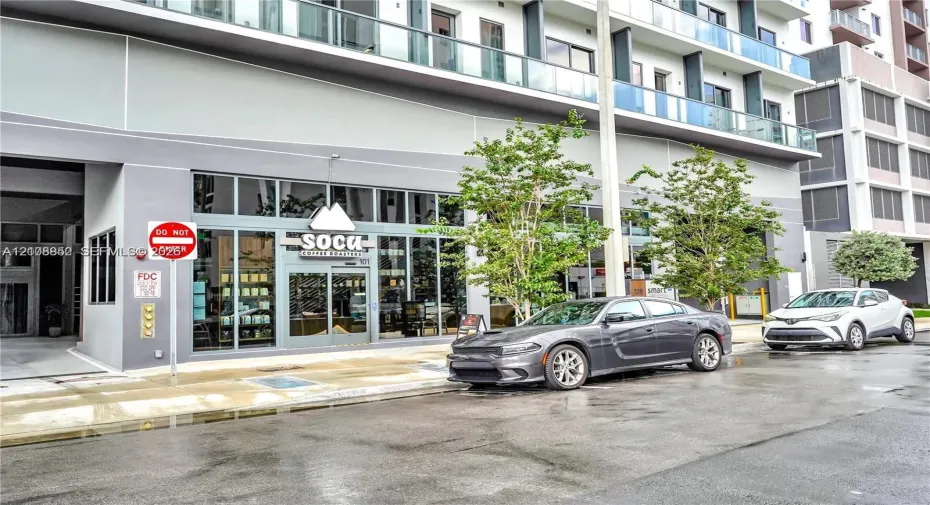 Commercial storefront featuring floor-to-ceiling glass windows, aluminum-framed entry door, and multi-level building facade with glass-railed balconies