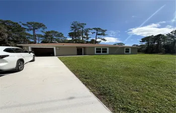Single-story residence featuring a concrete driveway, attached garage, and expansive lawn