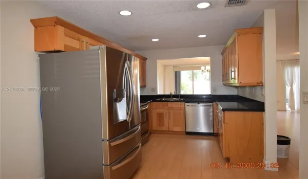 Kitchen featuring wood-finish cabinetry, dark solid-surface countertops, stainless steel appliances, and recessed lighting