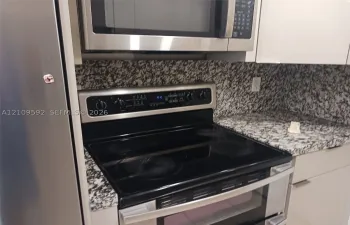 Kitchen featuring stainless steel appliances, a glass-top electric range, a built-in microwave, stone-finish countertops, and white cabinetry
