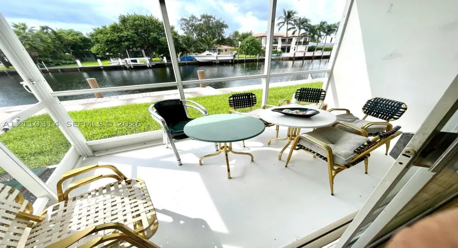 Screened-in patio with concrete flooring, overlooking a canal and private bulkhead