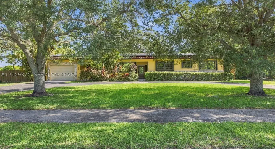 Single-story exterior featuring a stucco facade, an attached garage, a clay tile roofline, and mature landscaping