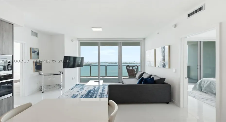 Open-concept interior featuring polished tile flooring, floor-to-ceiling glass doors, and integrated kitchen appliances