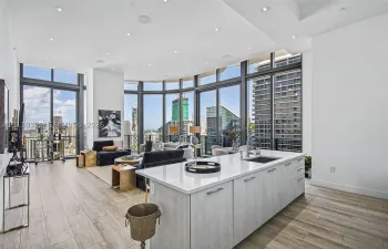 Open-concept kitchen featuring a center island with light-toned cabinetry and a stone-look countertop, floor-to-ceiling windows, wood-finish flooring, and recessed ceiling lighting