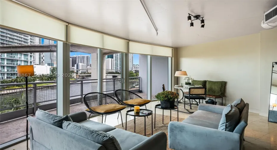 Floor-to-ceiling windows, stone-finish flooring, sliding glass door, and metal-railed balcony